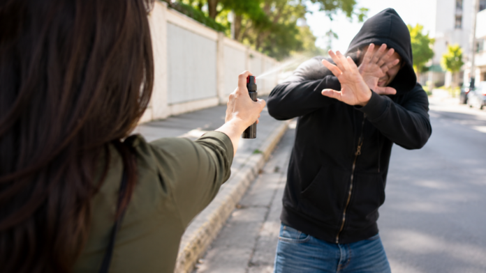 Mulher segurando spray de pimenta autorizado para defesa pessoal após publicação de nova lei federal.